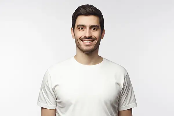 A smiling man wearing a white t-shirt, displaying his bright white teeth.